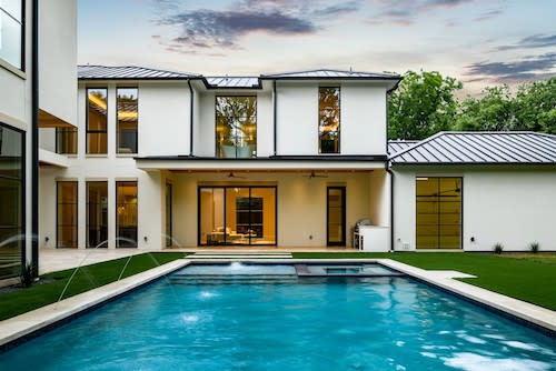 A contemporary house featuring a pool and patio, surrounded by a well-maintained exterior and an inground pool with a spa.