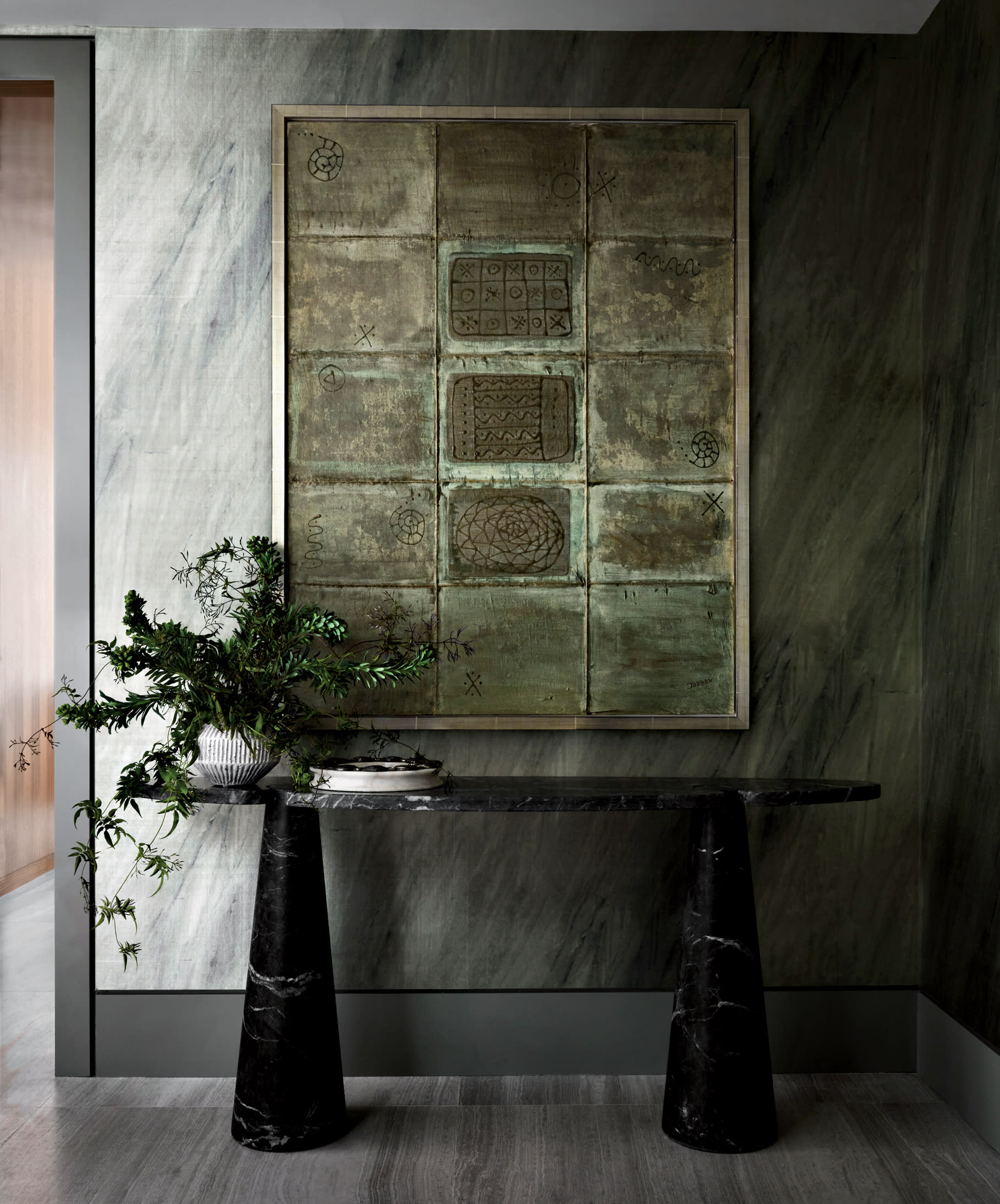 moody hued entryway with a vintage artwork above a black sculptural console table