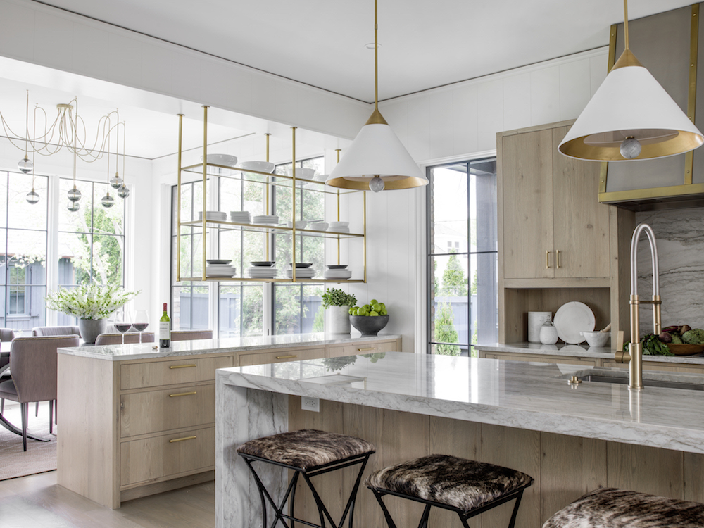 Character London Oak Cabinetry, marble waterfall island, brass open shelving that hangs from ceiling, white and brass pendant lights.