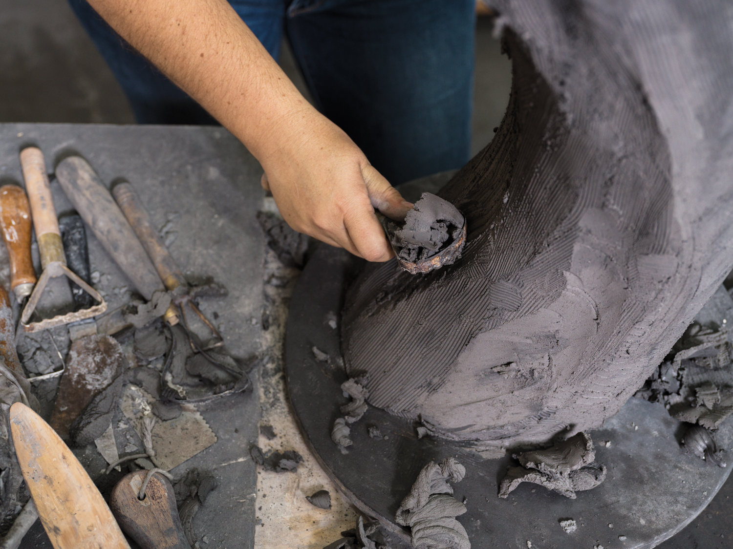 Detail shot of sculptor Beverly Morrison's hand sculpting dark clay