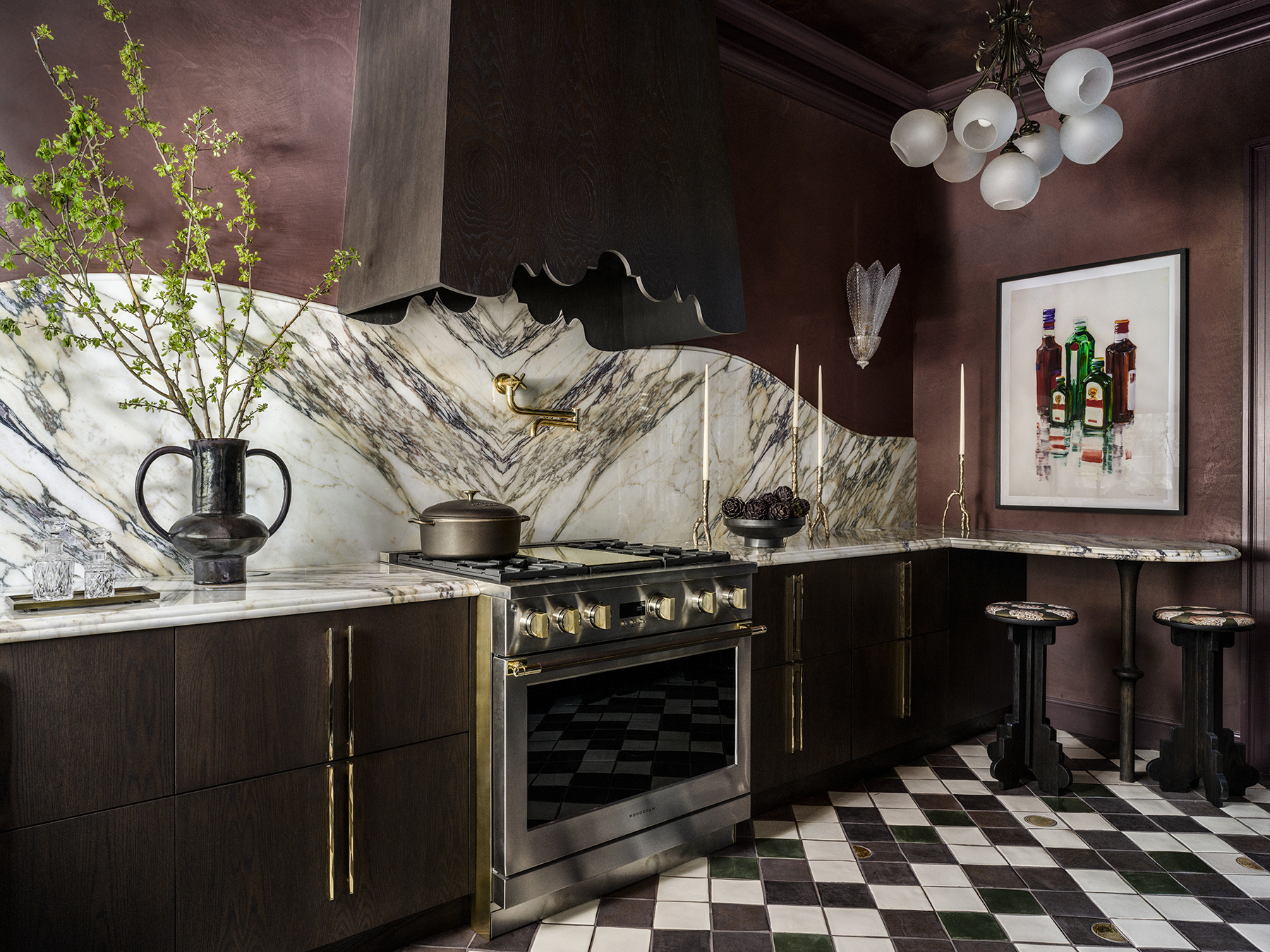 A kitchen has a scalloped range hood, veined marble, black and white tile.