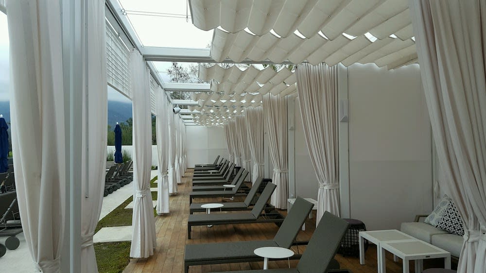 white awnings and drapes on patio with lounge chairs