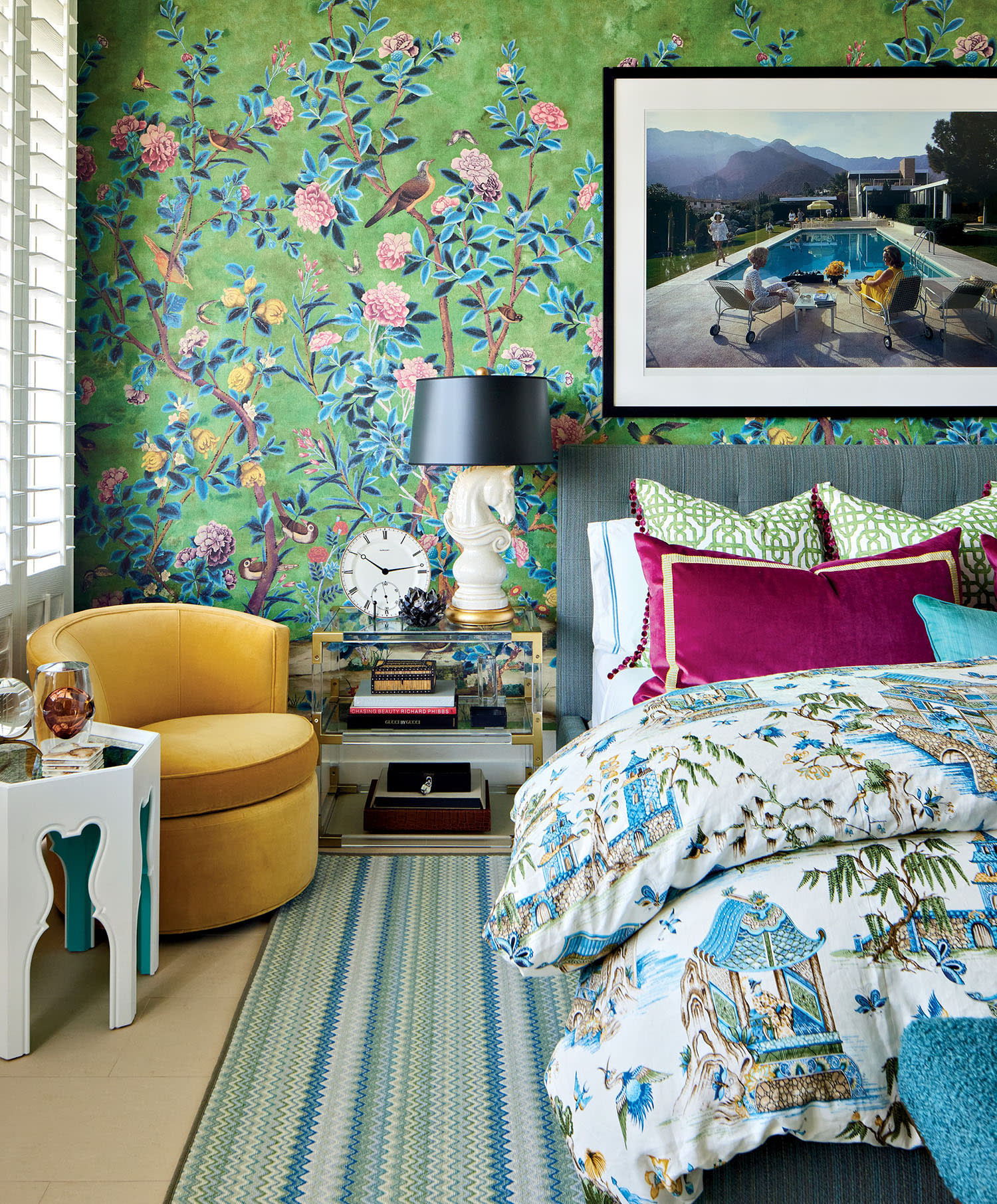 Chic bedroom with vibrant floral wallpaper, colorful bedding, and a yellow chair