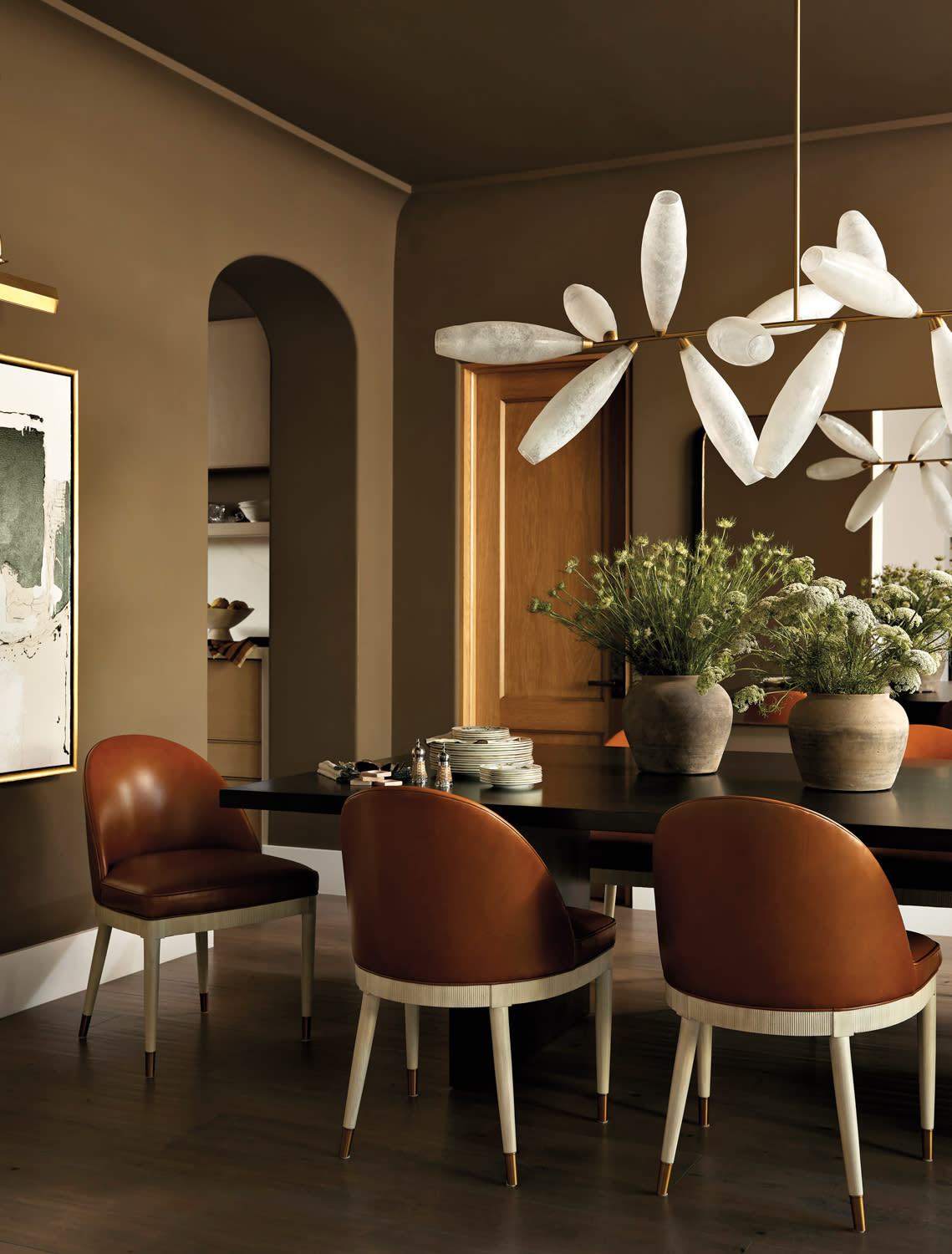 dining area with a walnut rectangular dining table, rounded back leather chairs, and a vintage Murano glass chandelier by Nicole Green