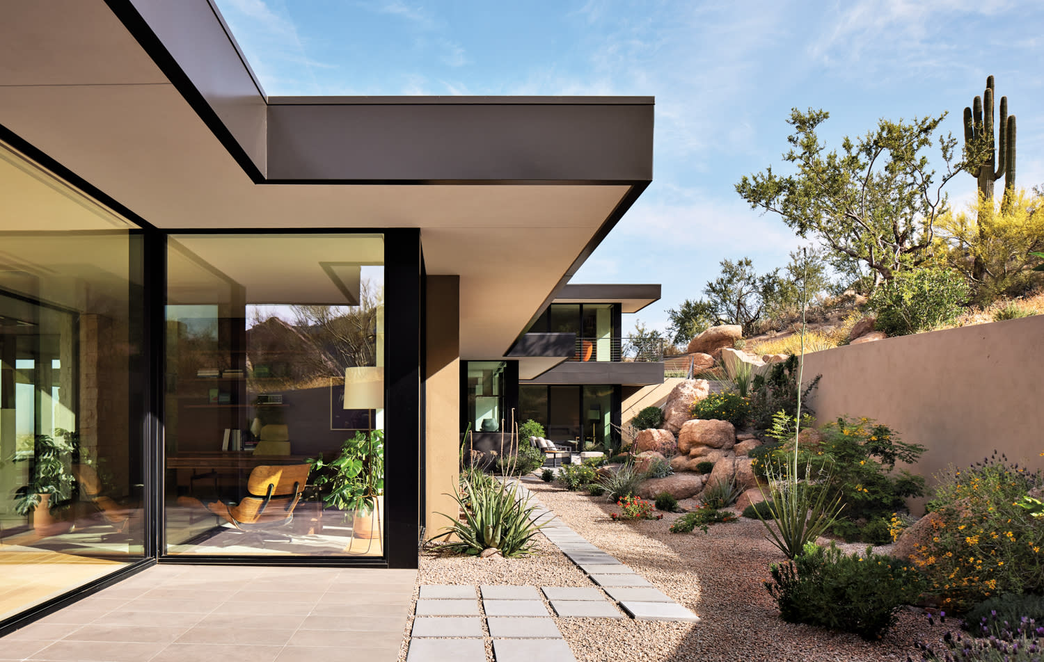 a garden with gravel, desert flora and fauna outside a contemporary home by Charles R Stinson