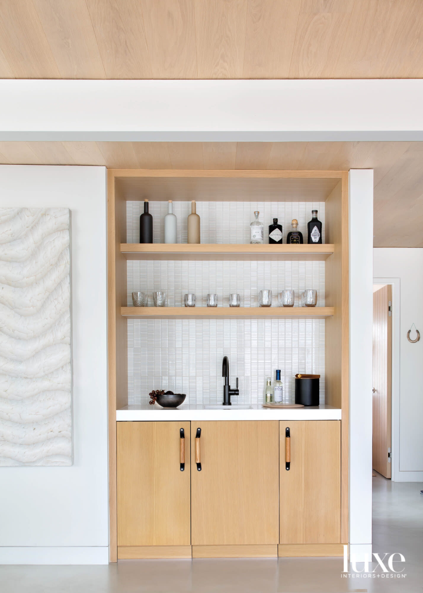 A bar in the living room has light colored cabinetry
