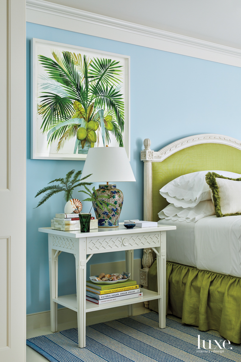 bedroom with light blue walls, lime green bed, white nightstand and tropical artwork