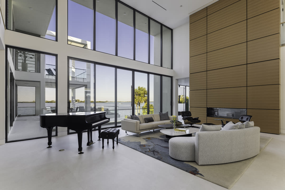 A well-lit living room with a grand piano and expansive windows, offering a serene and elegant ambiance.