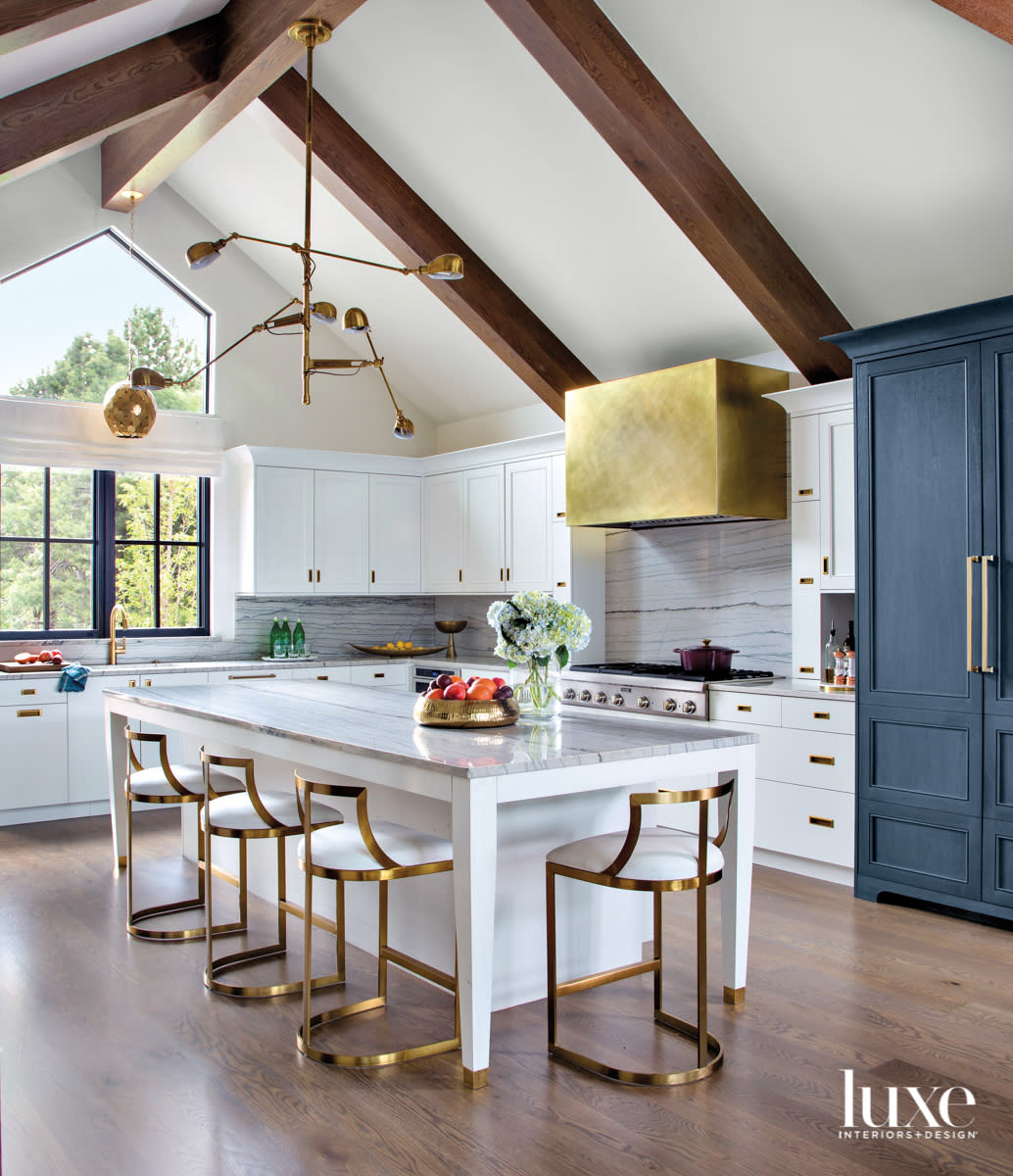 white kitchen with blue accent cabinet and brass stools