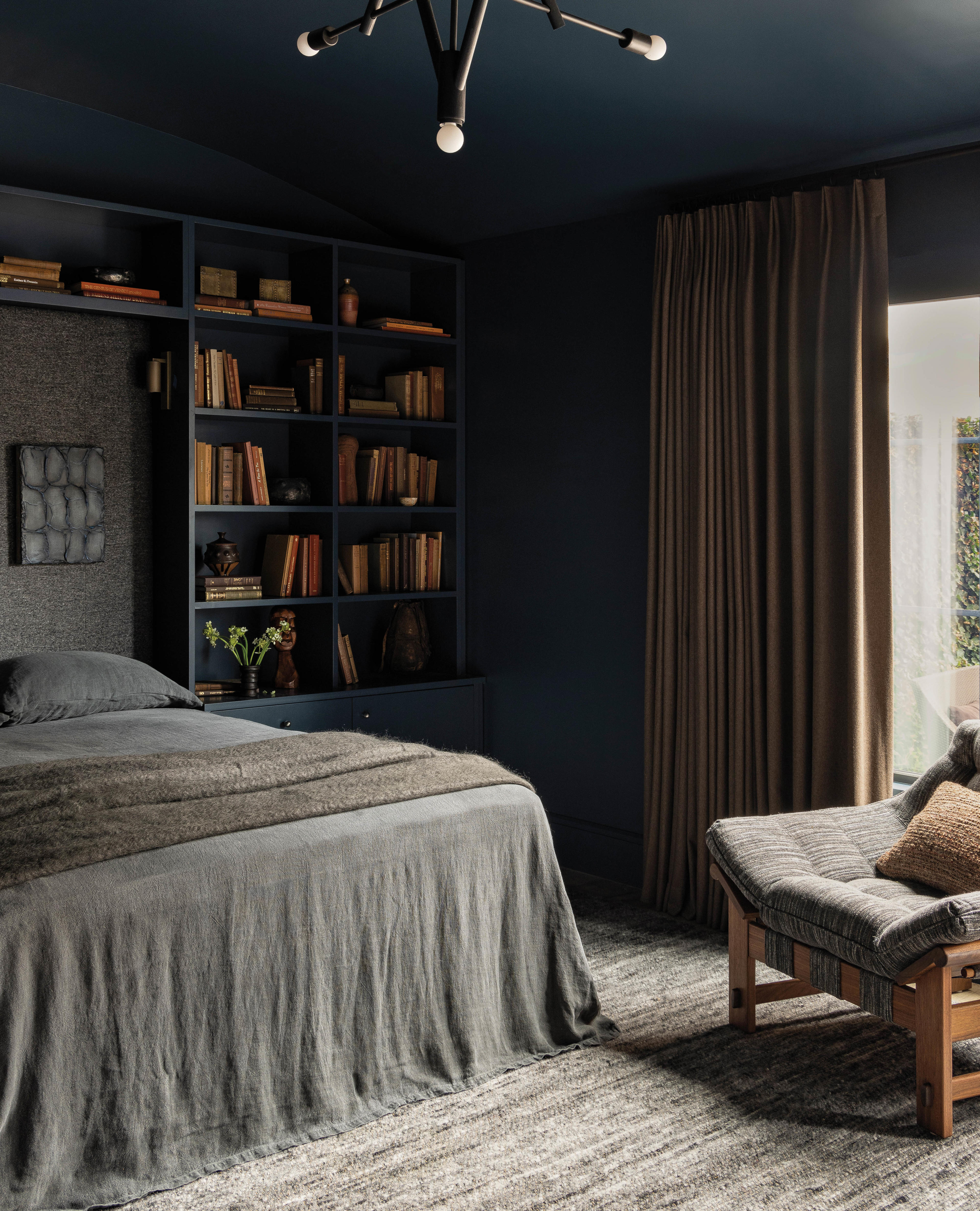 moody bedroom with dark blue built in bookshelves and gray bedding 