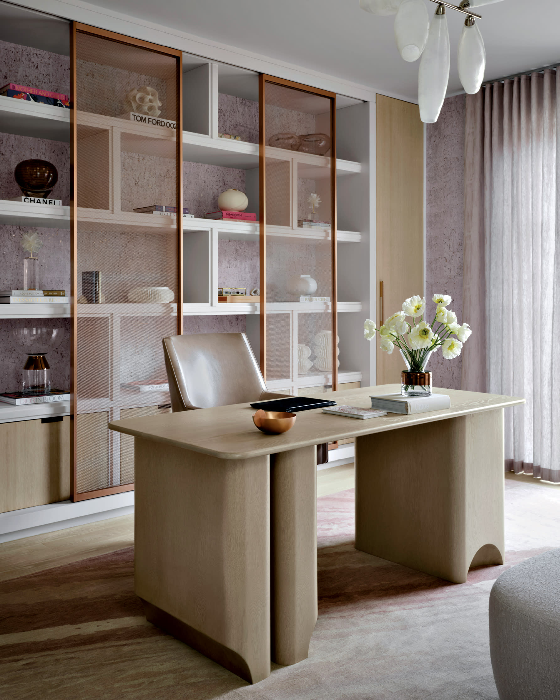 rose-gold mesh covers shelving behind a white oak desk in a home office