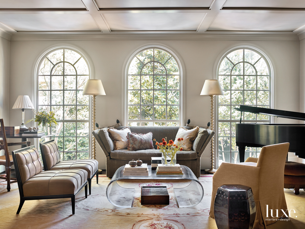 large living room with three tall windows, clear coffee table and lots of seating