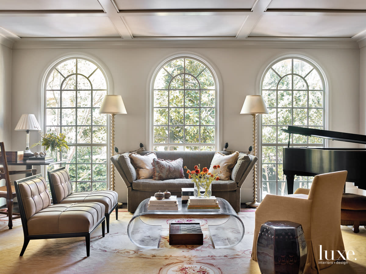 large living room with three tall windows, clear coffee table and lots of seating