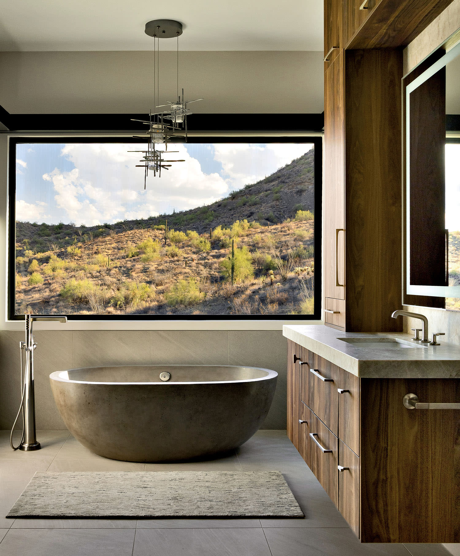 A spacious bathroom featuring a large tub with a scenic view of the mountains through a window.
