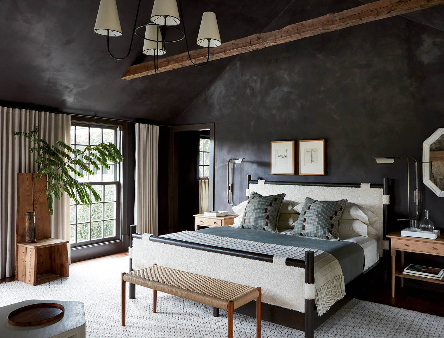 A bedroom with dark walls, a white rug, and a bed made up with a quilt and accent pillows.