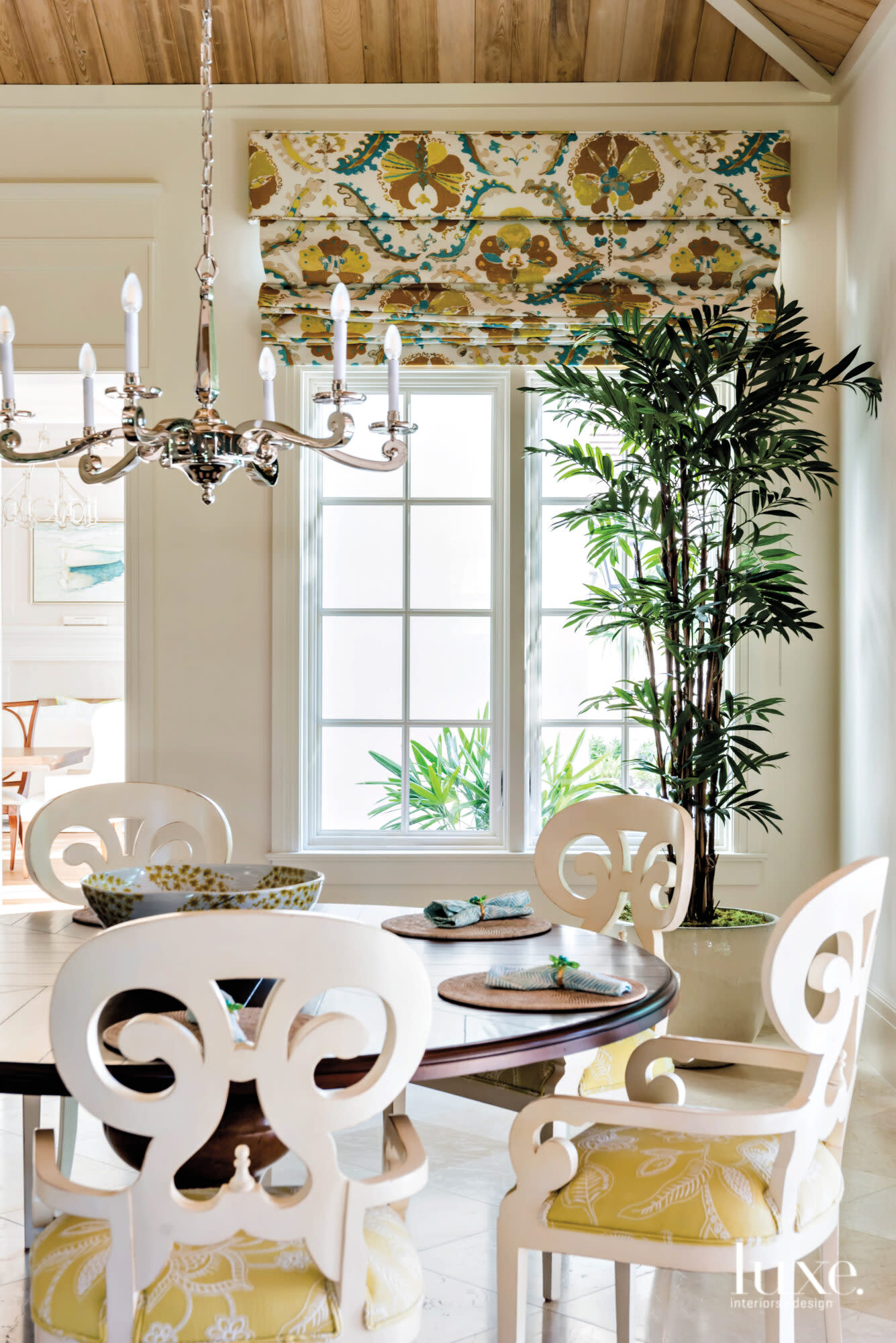 Dining area with yellow and white chairs around a wood table.