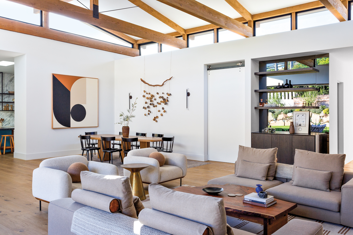 light-filled living and dining area with clerestory windows, exposed beams and seating areas