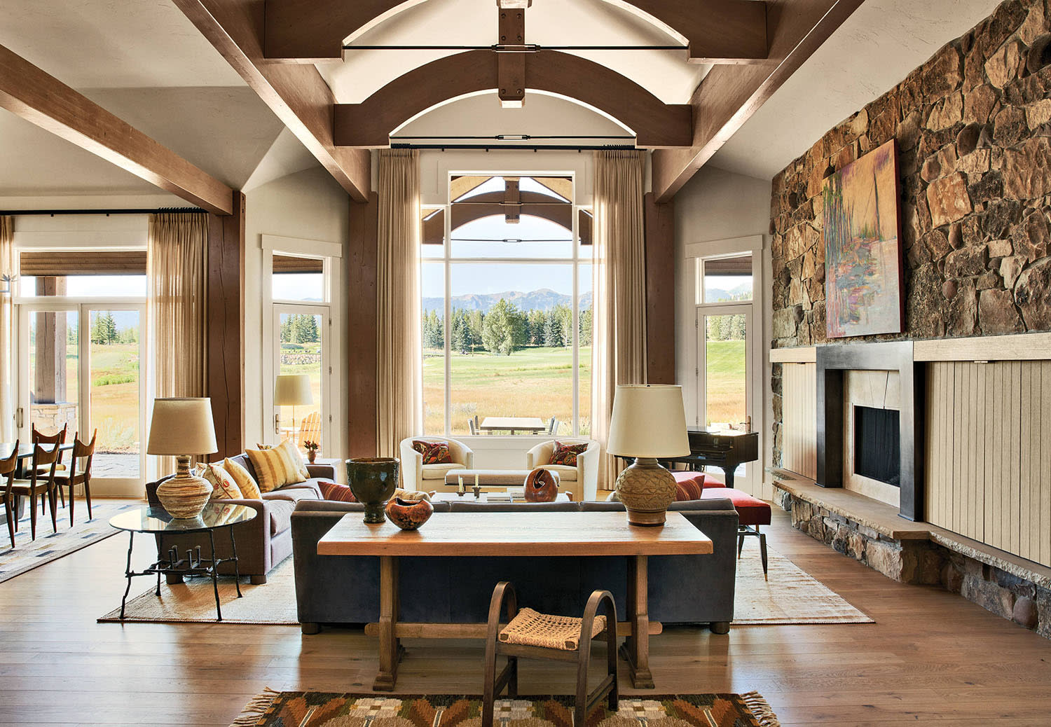 open living room of a mountain home with a stone surrounded fireplace and vintage furnishings