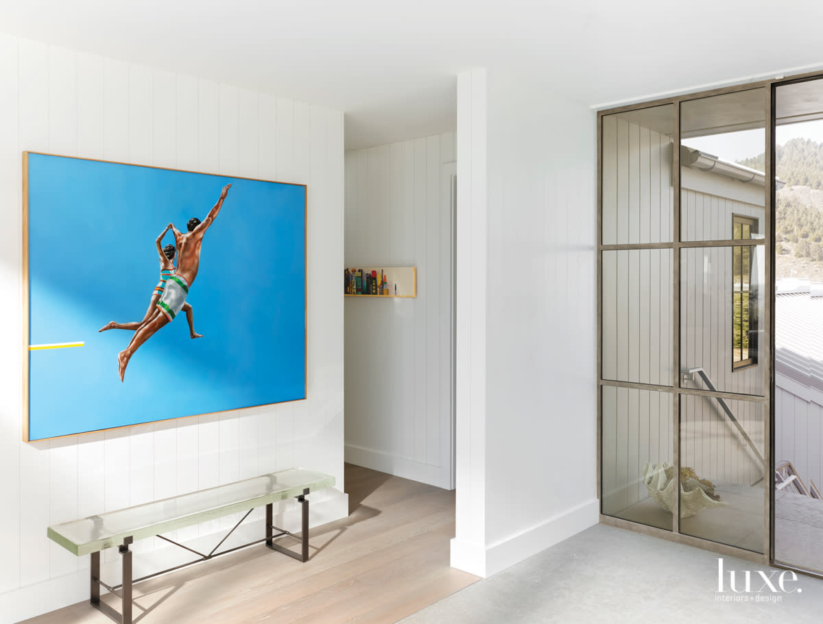 A bright blue painting adds a pop of color to this all-white entryway.