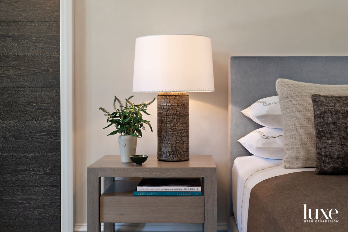 A textured ceramic lamp is on a nightstand.