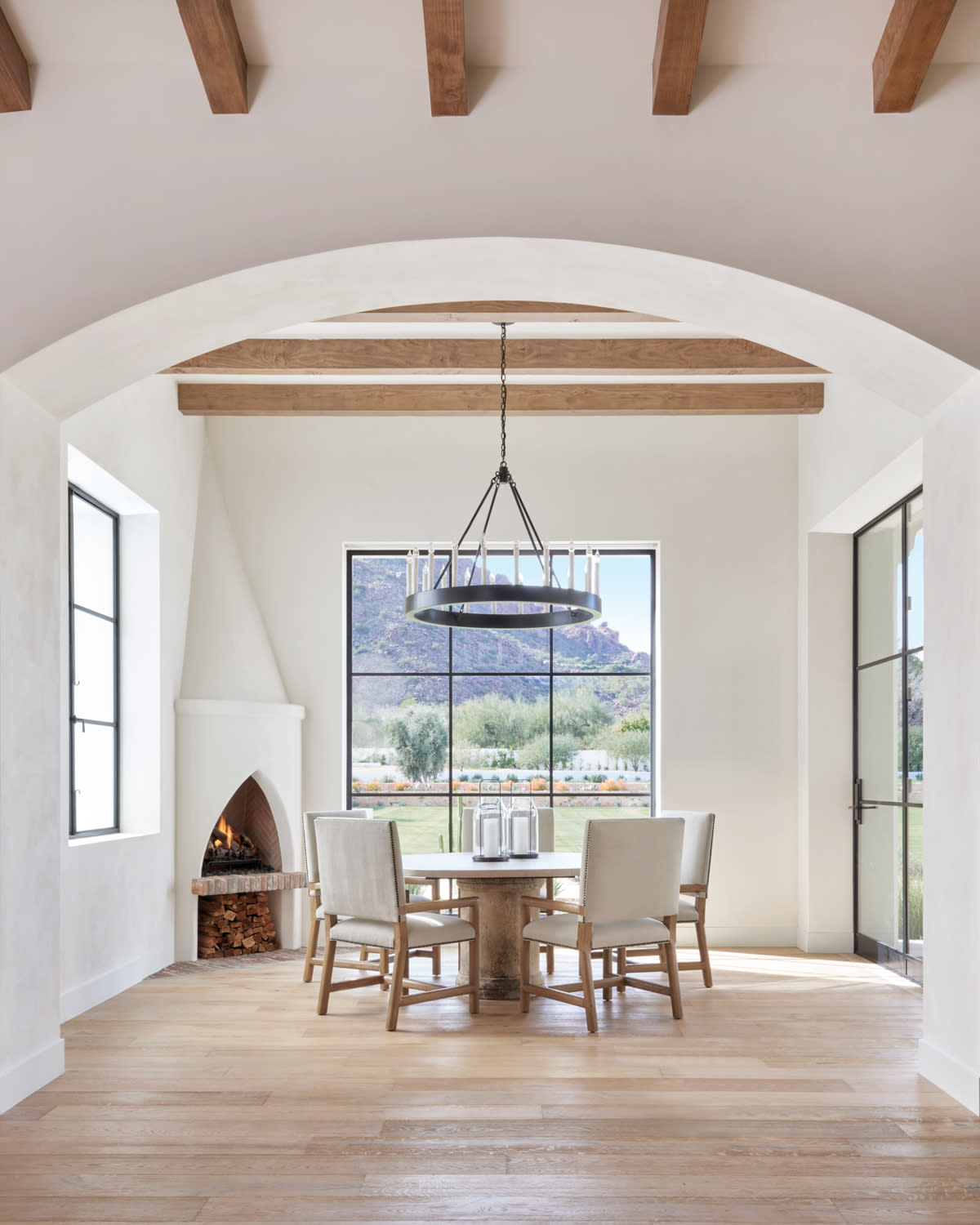 white dining room with wood beams, a beehive fireplace and a round table