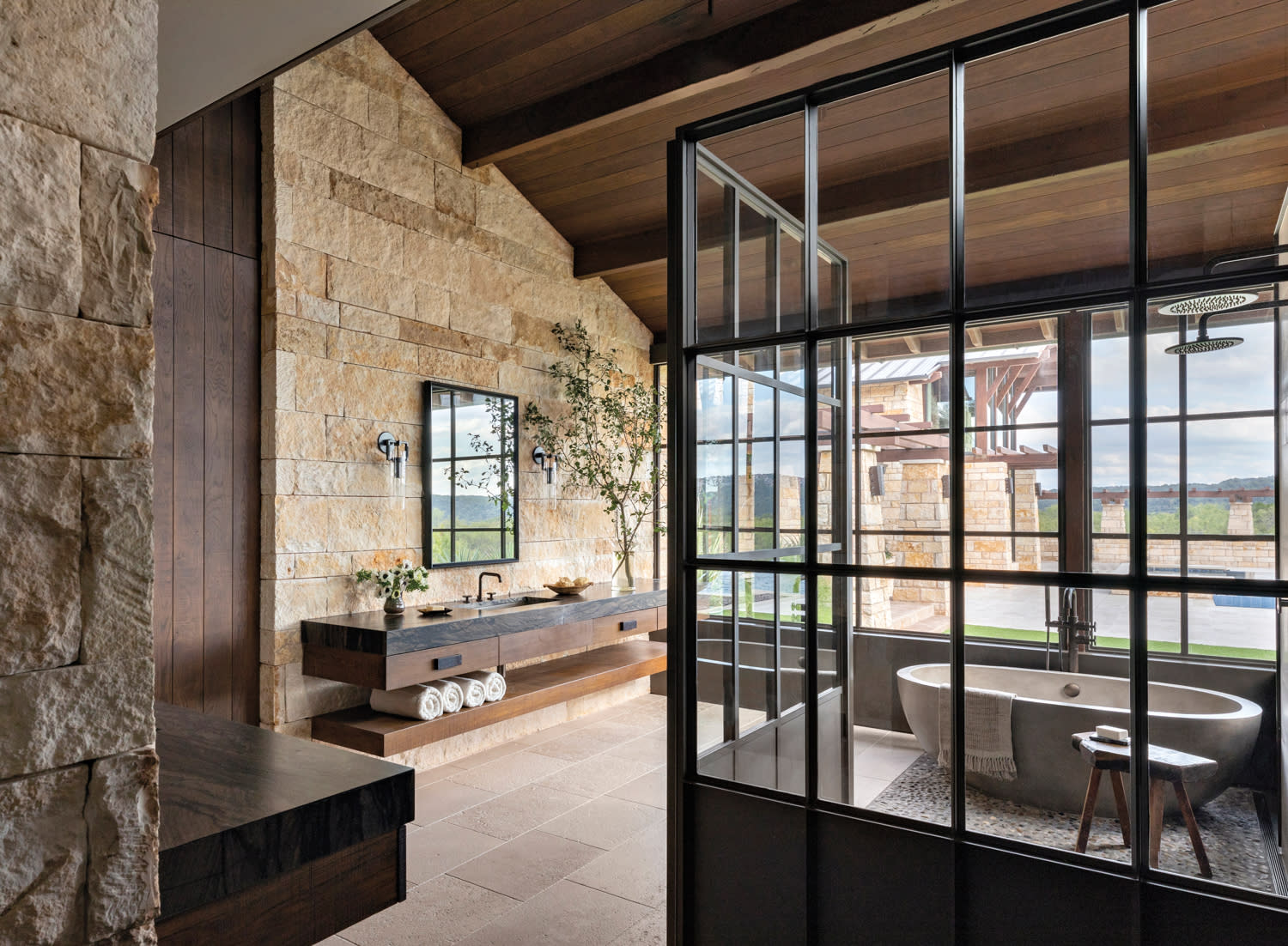 primary bathroom with stone walls and free-standing tub in home by Blair Burton