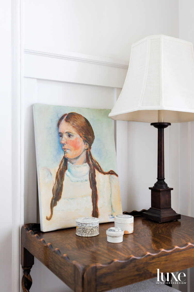 Detail of bathroom with scallop-edge table, painting and lamp