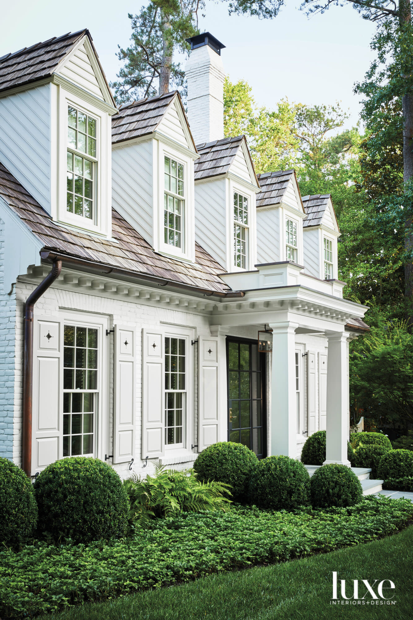 Facade of traditional home with five dormer windows and portico