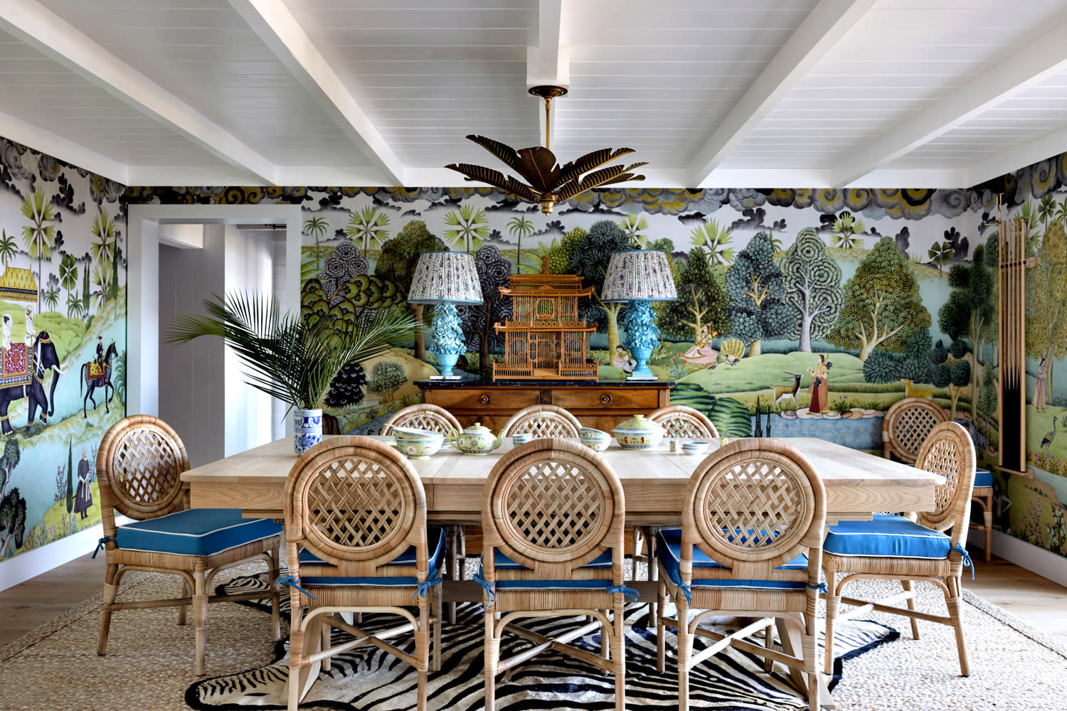 tropical dining room with an Indian-inspired mural lining the walls and a palm tree ceiling fixture