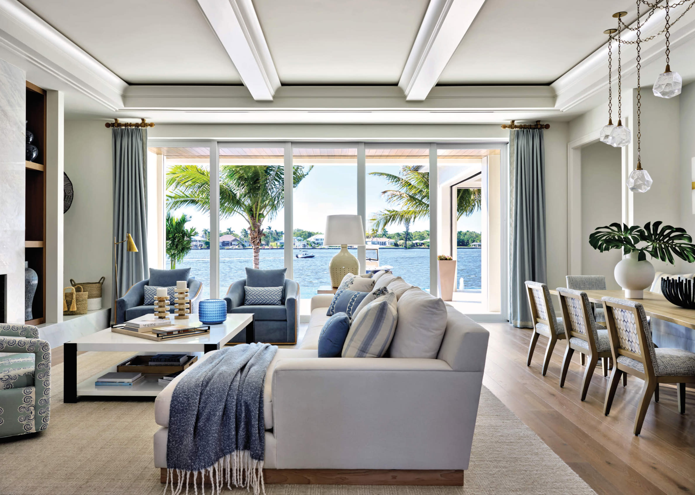 coastal white living room opens to pool with blue accents and white couch 