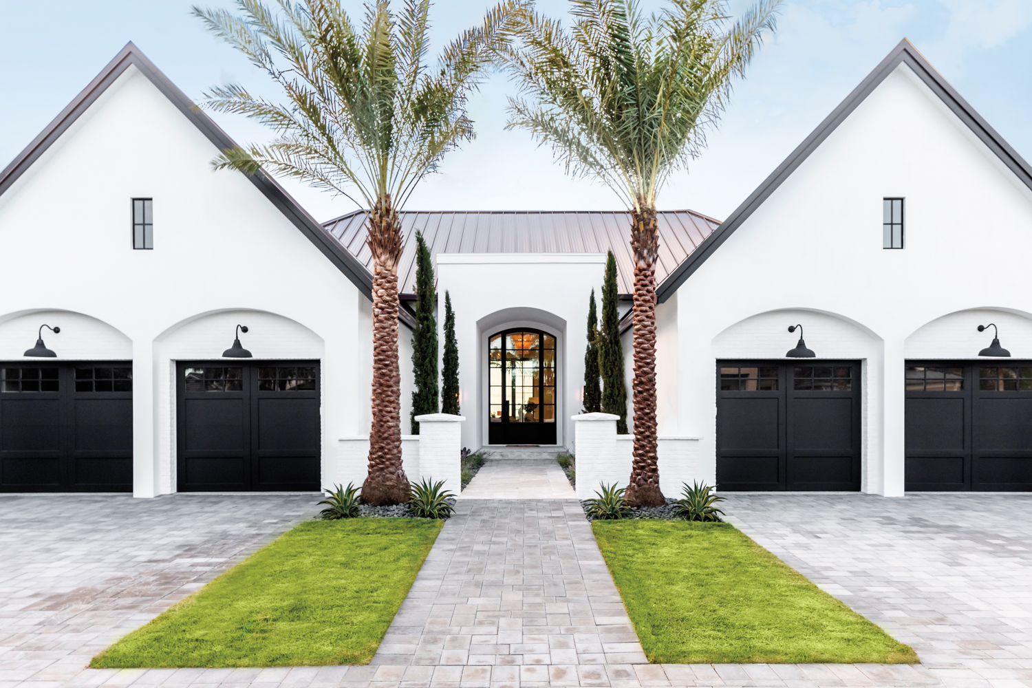 front exterior of white home by Kelsey McGregor with two black garage doors and two palm trees