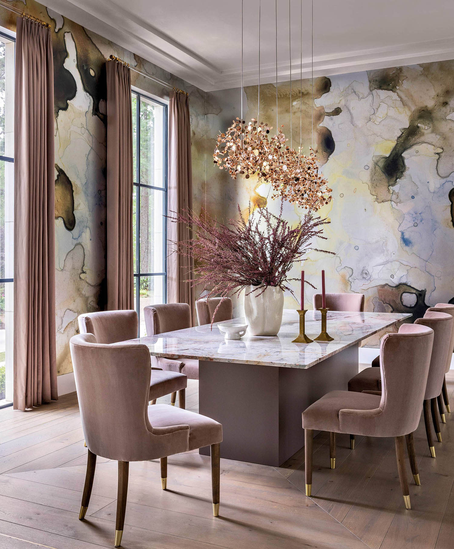 Wallpaper with a watercolor-style design sits at the back of a dining room near a table and chairs.