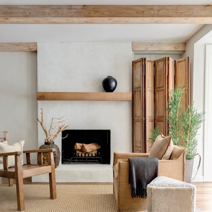 "A natural palette of earth tones, textured fabrics, stones, metals and woods adds warmth and interest to each living space. In the hearth room, a cedar mantel beam, antique folding screen and rugged medicine chair pop against the freshly plastered fireplace wall.