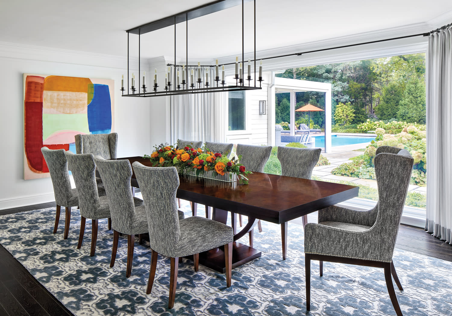 dining room with abstract painting, long rectangular wood table and gray chairs by Martin Horner