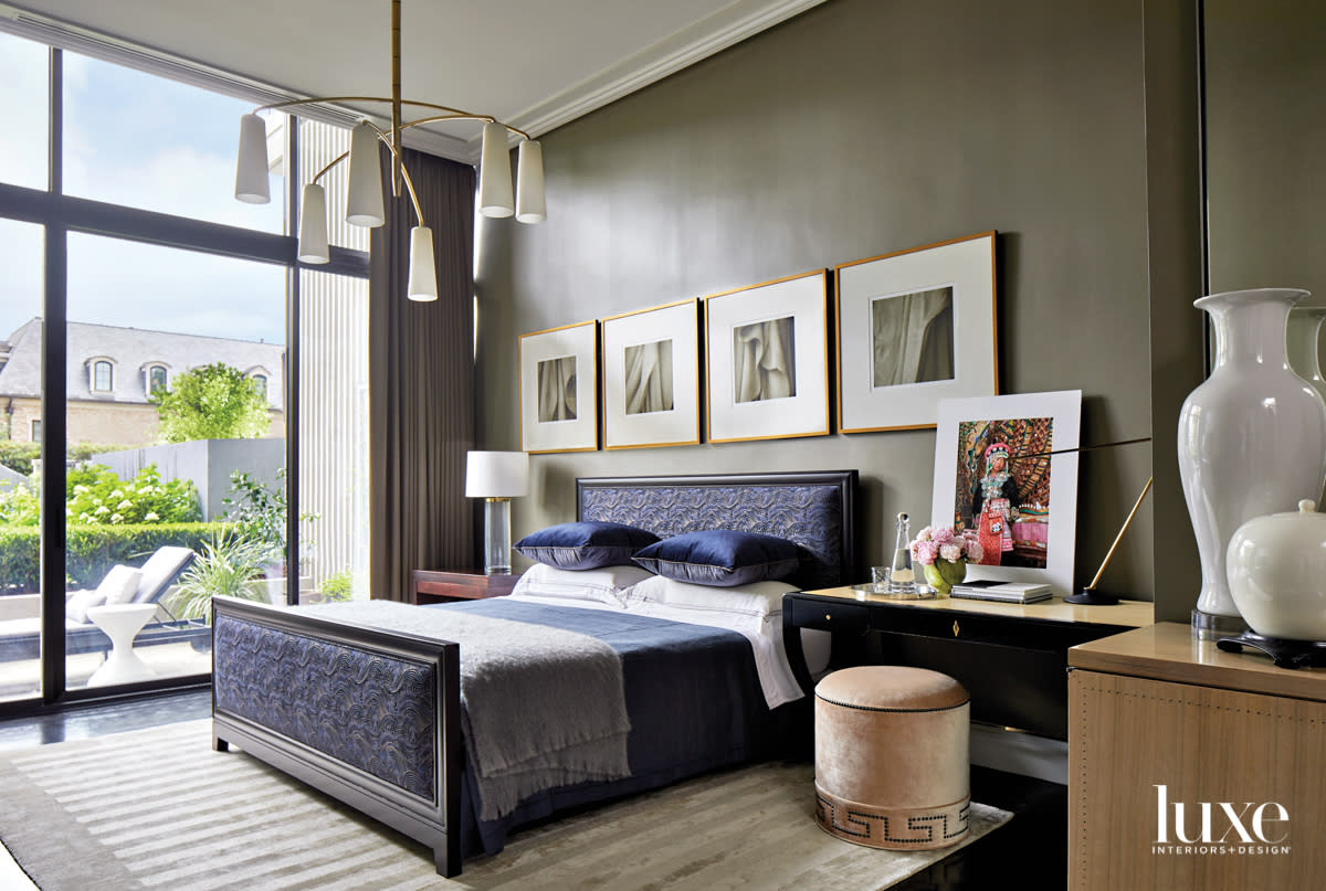 Sleek bedroom with navy upholstered bed, steely gray walls and quad of framed artworks