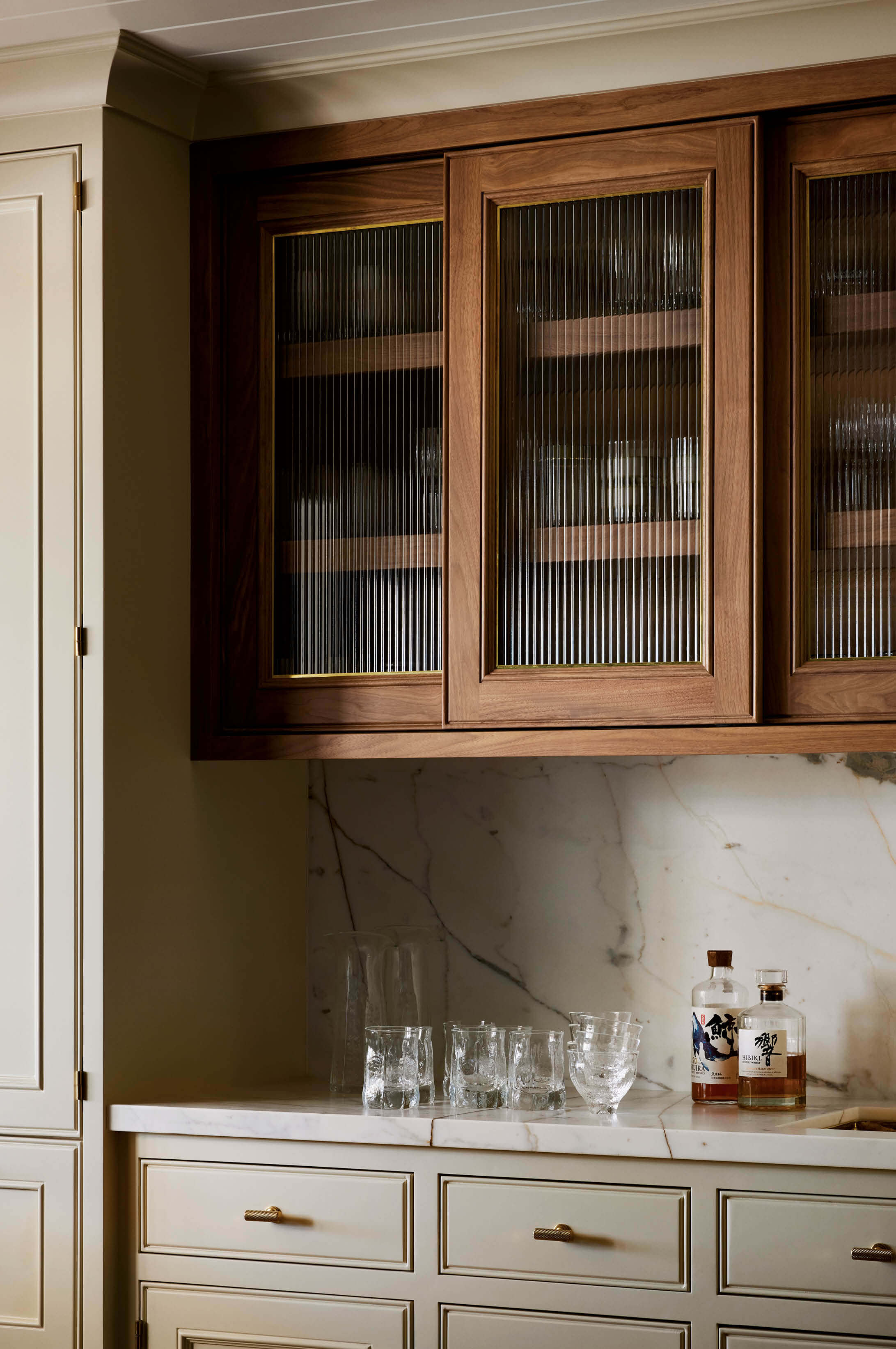 kitchen bar with walnut upper cabinets with reeded glass fronts