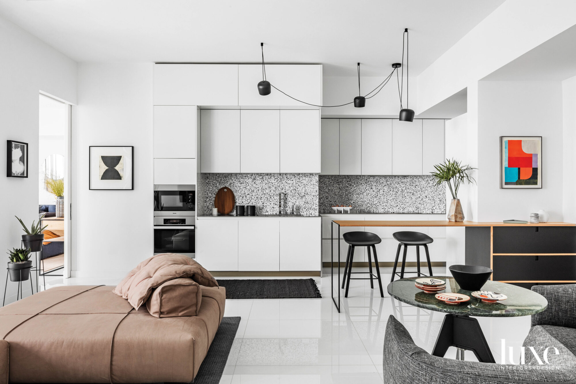 miami beach condo with oversize ottoman, white kitchen, black stools and black lighting fixture