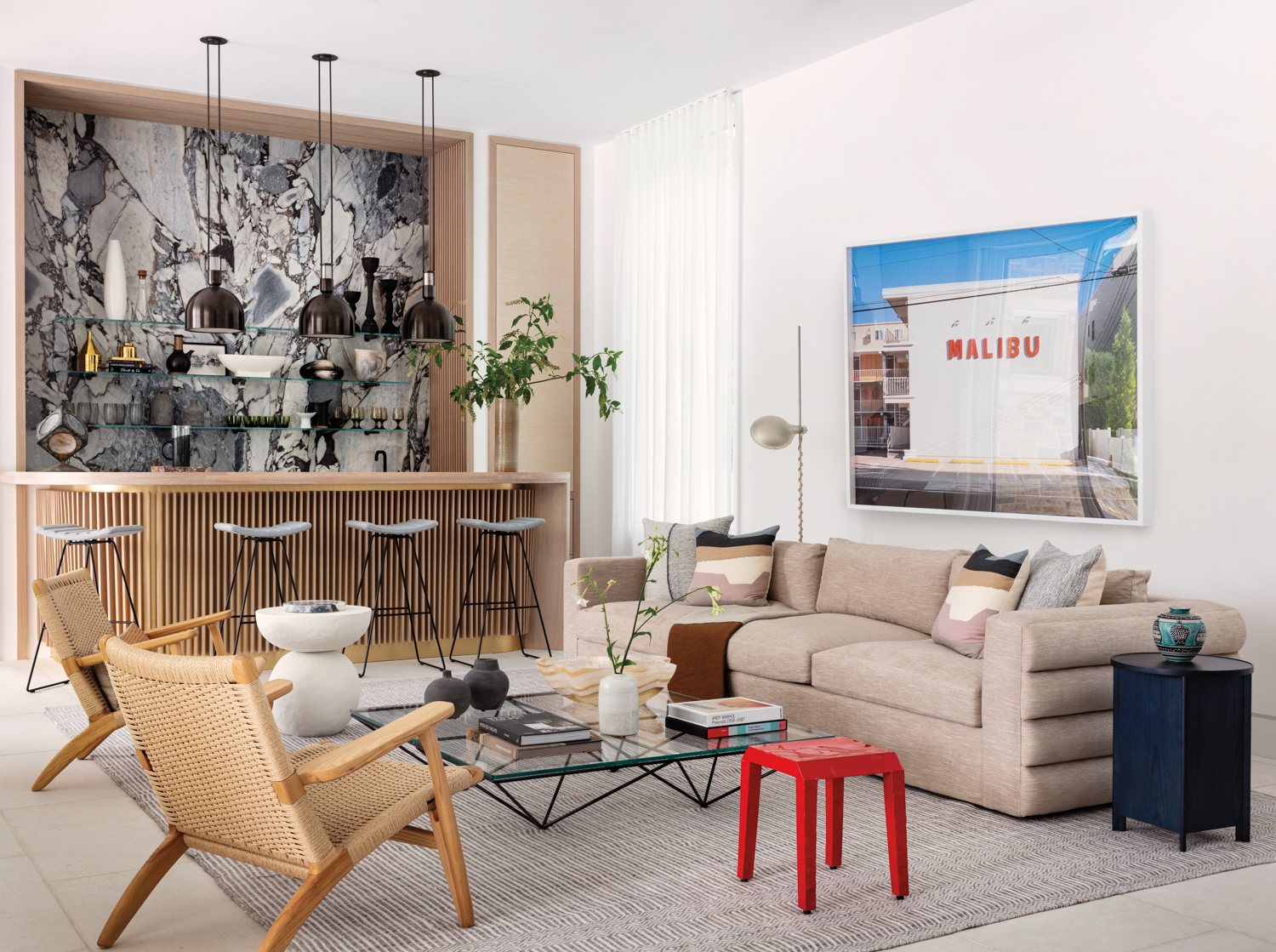 living space of pool house with glass coffee table, brown chair and artwork