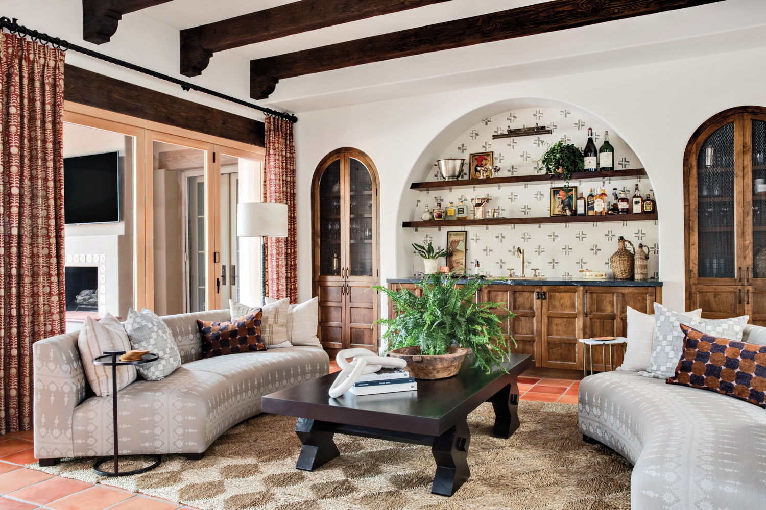 living room with arched inset bar, with two curved sofas, seagrass rug and dark coffee table by Design Alchemy