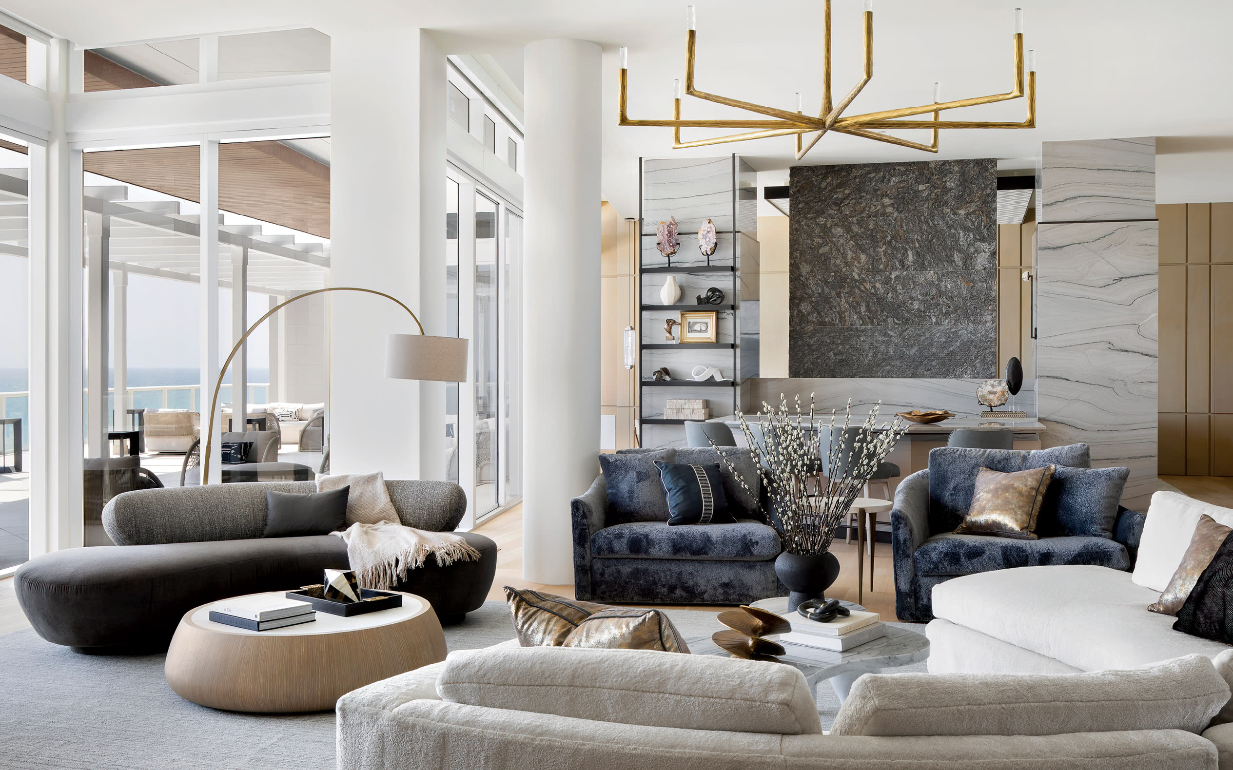 expansive modern living room with sculptural lighting fixtures and views of the ocean outside