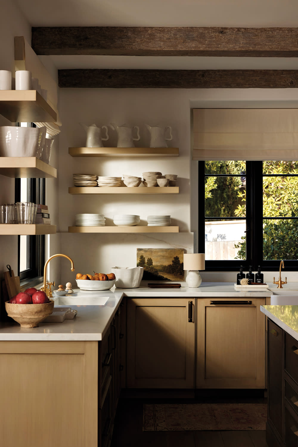 kitchen with marble counters, lamp, artwork and shelves with neutral ceramic dishware in home by Nicole Green