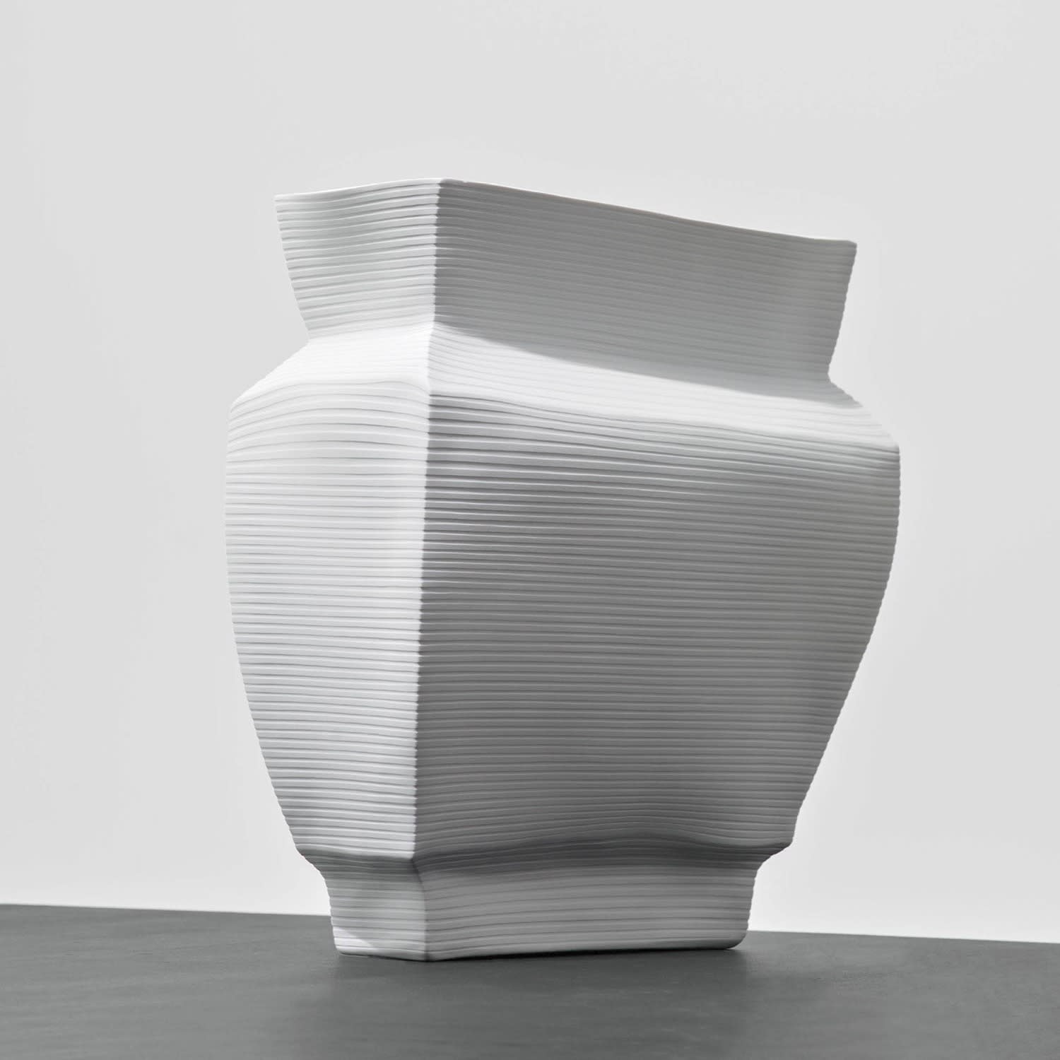 An angular white vase sits on a table.