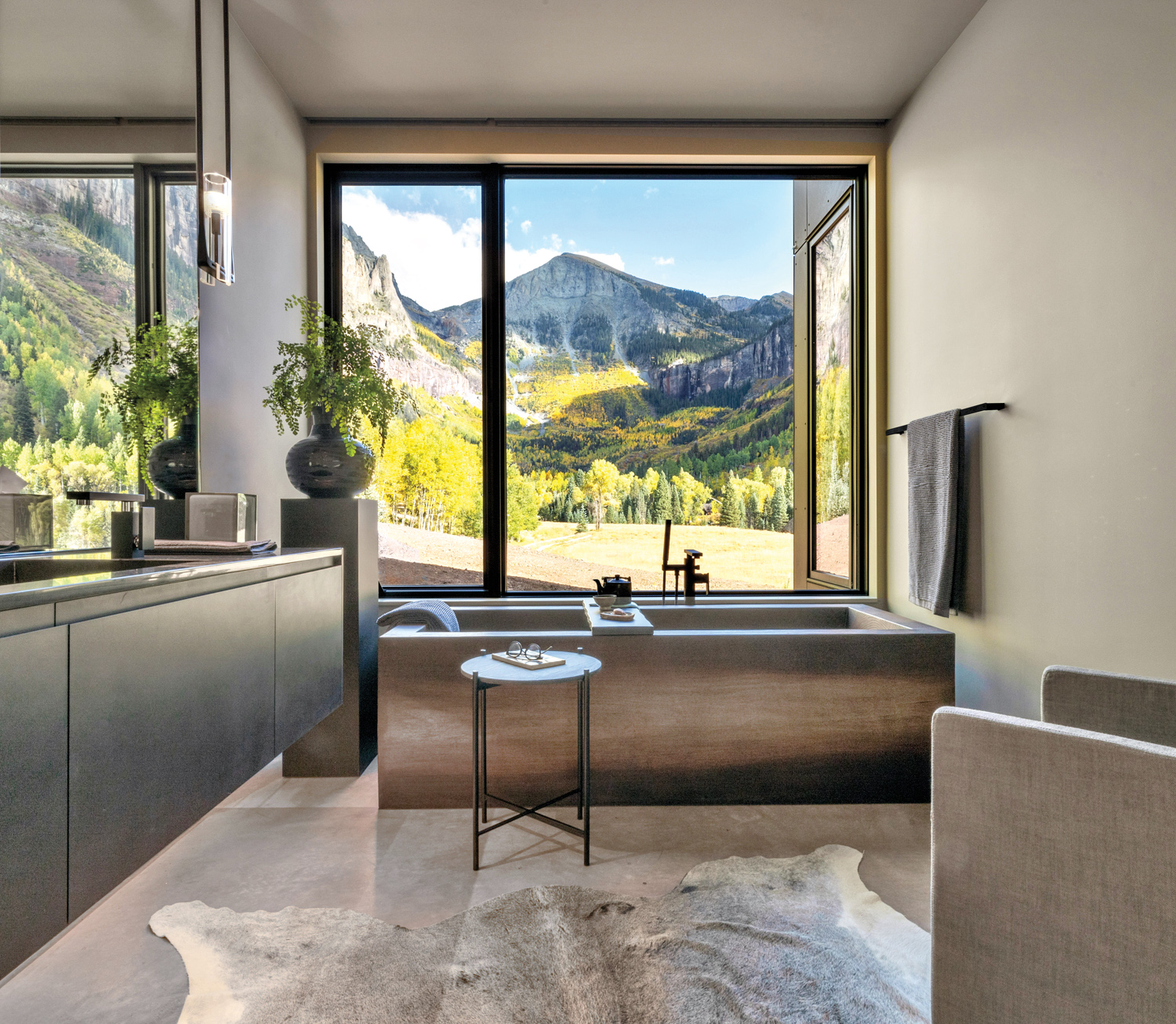 Bathroom with freestanding tub in front of window wall that looks onto panoramic views of a mountain