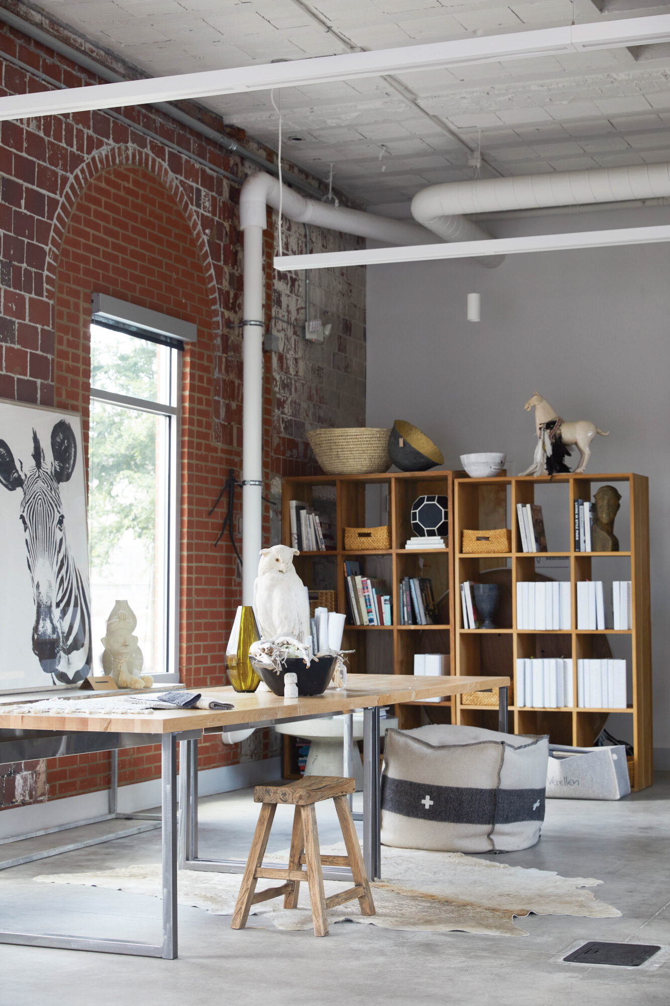 Loft-style office with exposed brick, open shelves and zebra artwork