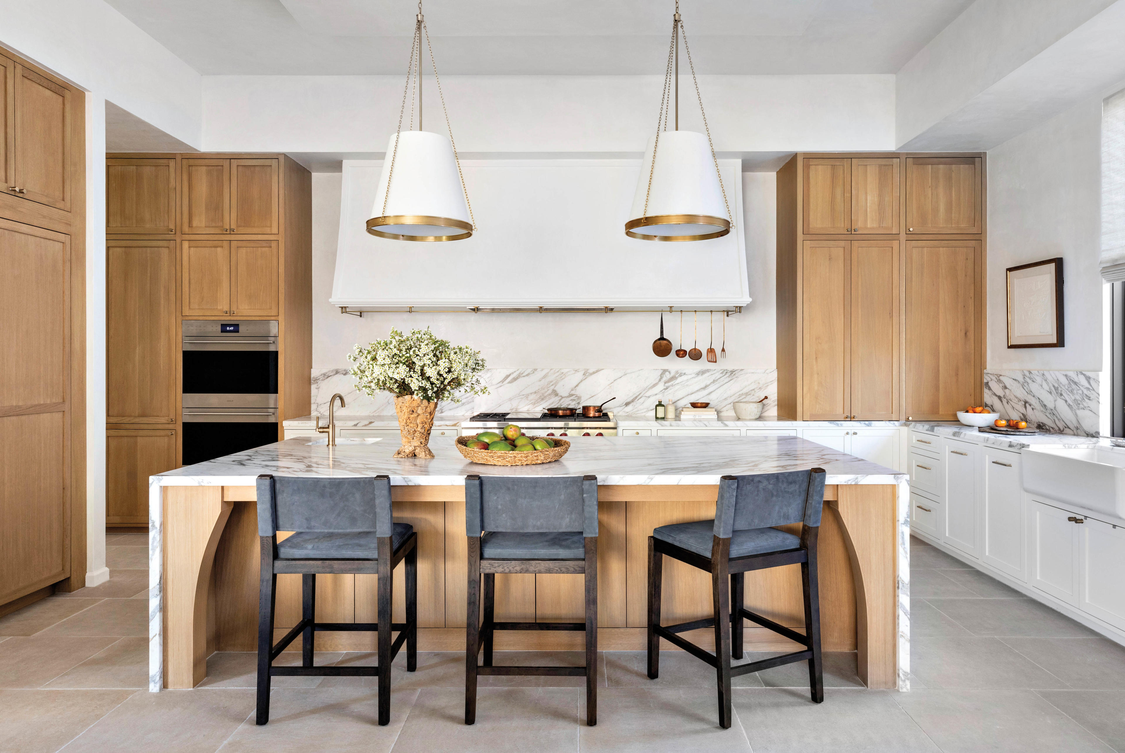 kitchen with white oak cabinetry and double ovens with leather counter stools at island