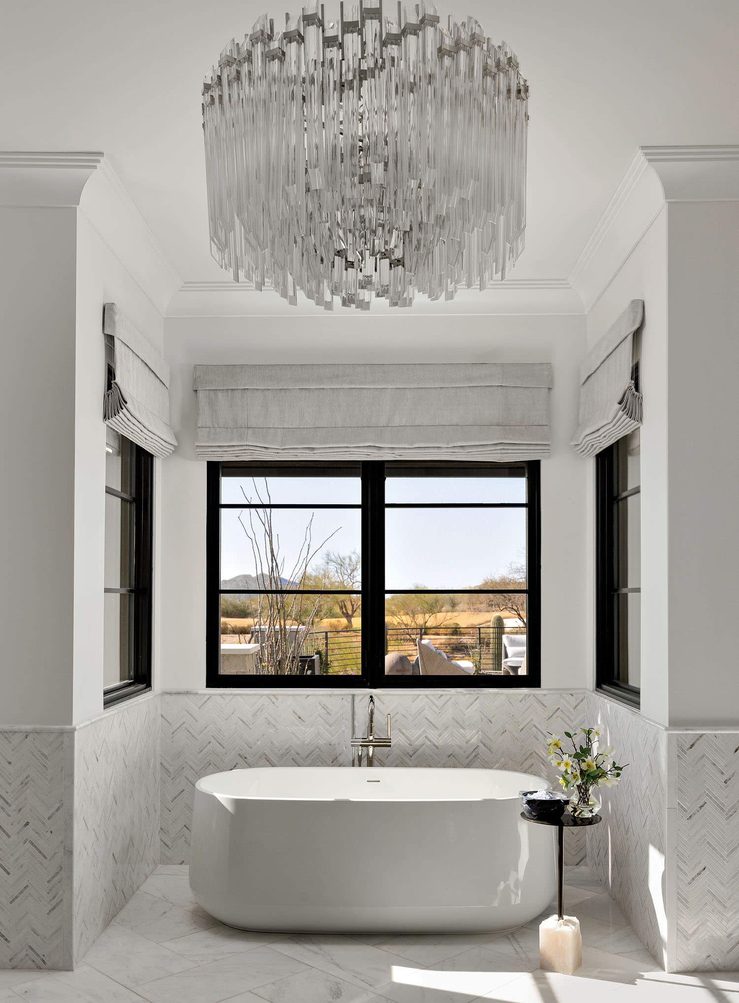 bathroom with a Visual Comfort & Co. crystal chandelier above a freestanding tub