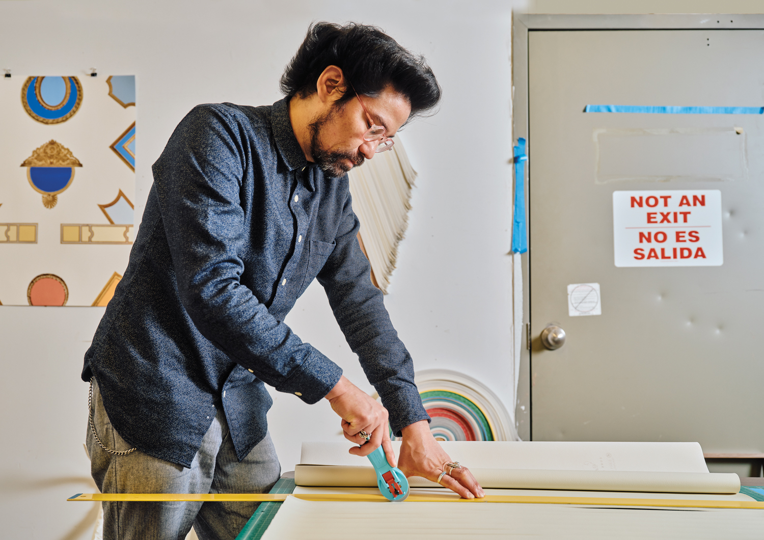 artist Derrick Velasquez with cutting tool at table, cutting vinyl strips