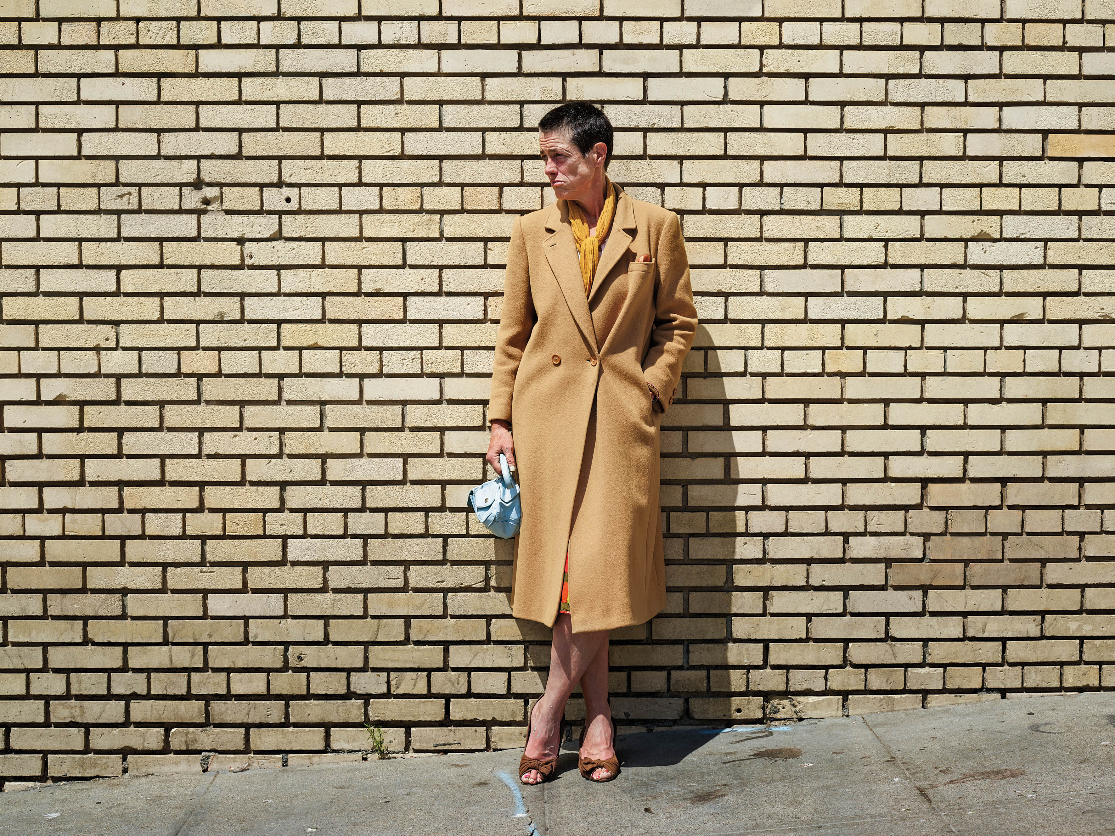 person posing in front of a brick wall on the street