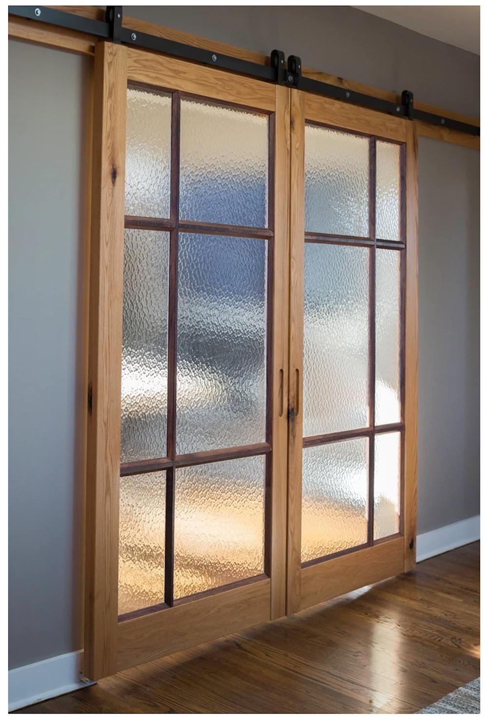 Wood and glass doors hang from a metal sliding track at the top.