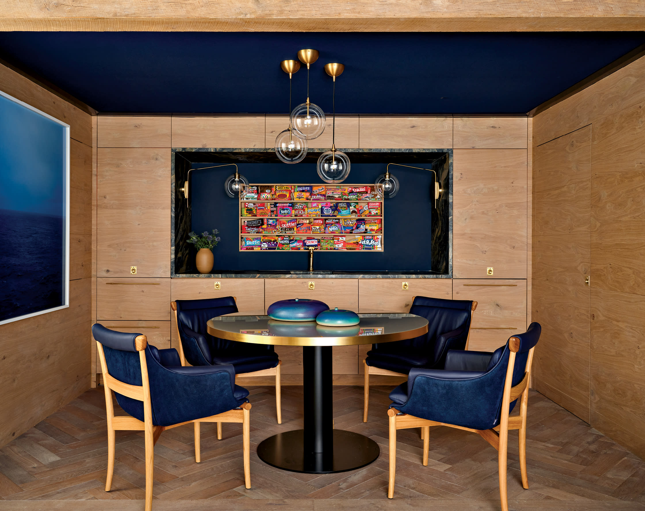 whimsical artwork of candy lines the wall of an oak and dark blue lounge